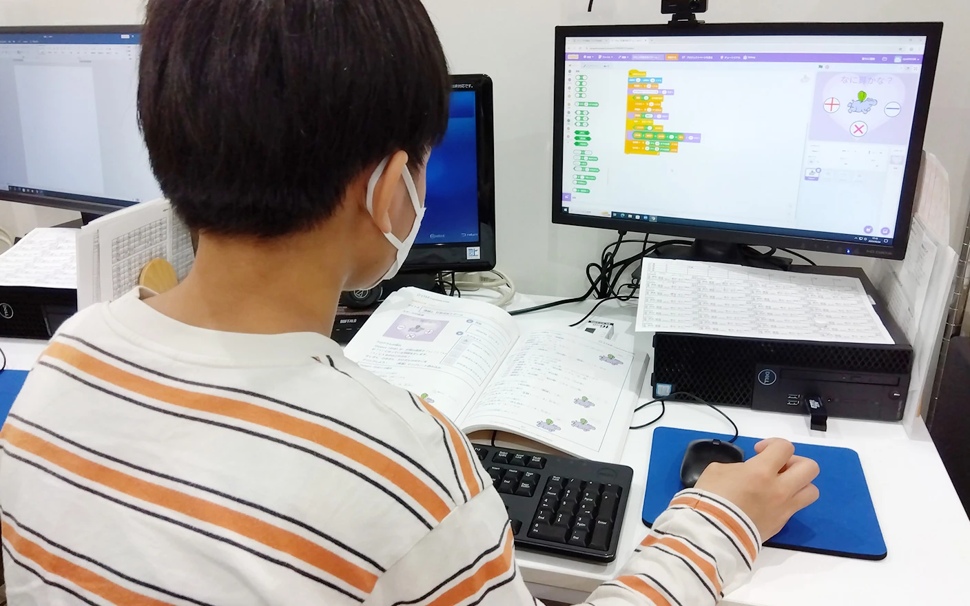ビジュアルプログラミングの学習に取り組む生徒の背中