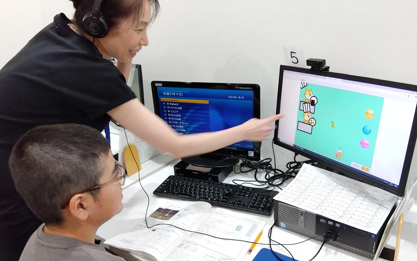 講師が生徒にパソコンを使ってプログラミングを教えている