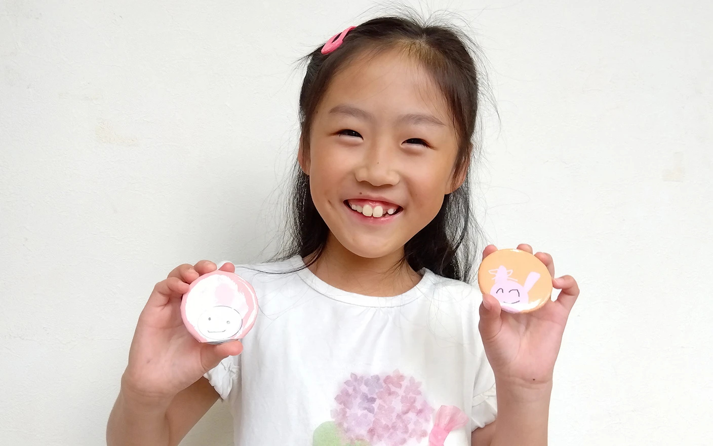 オリジナル缶バッジを見せる生徒の女の子