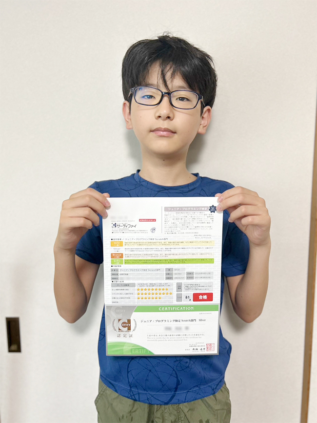 合格証明書を手にして自宅の部屋でたっている受講生